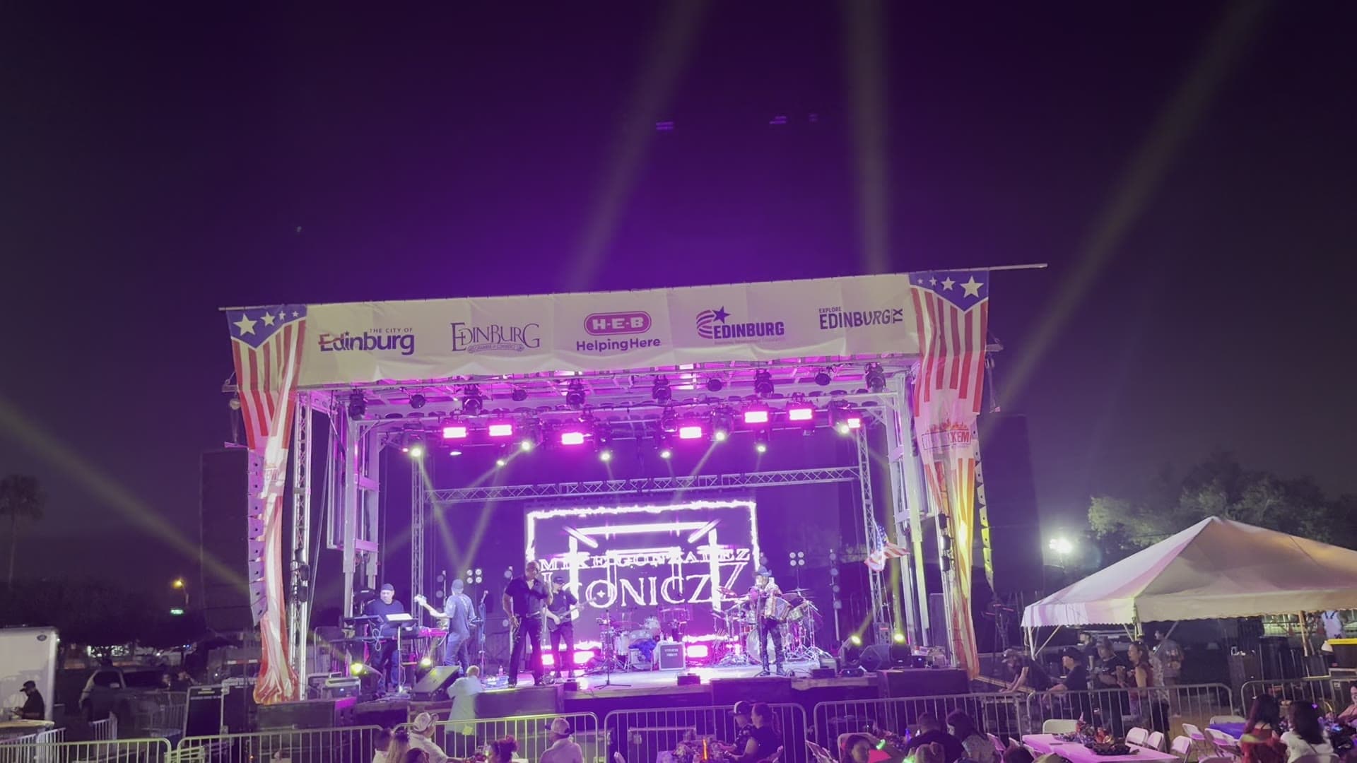 Outdoor concert stage with purple lighting and a large LED screen