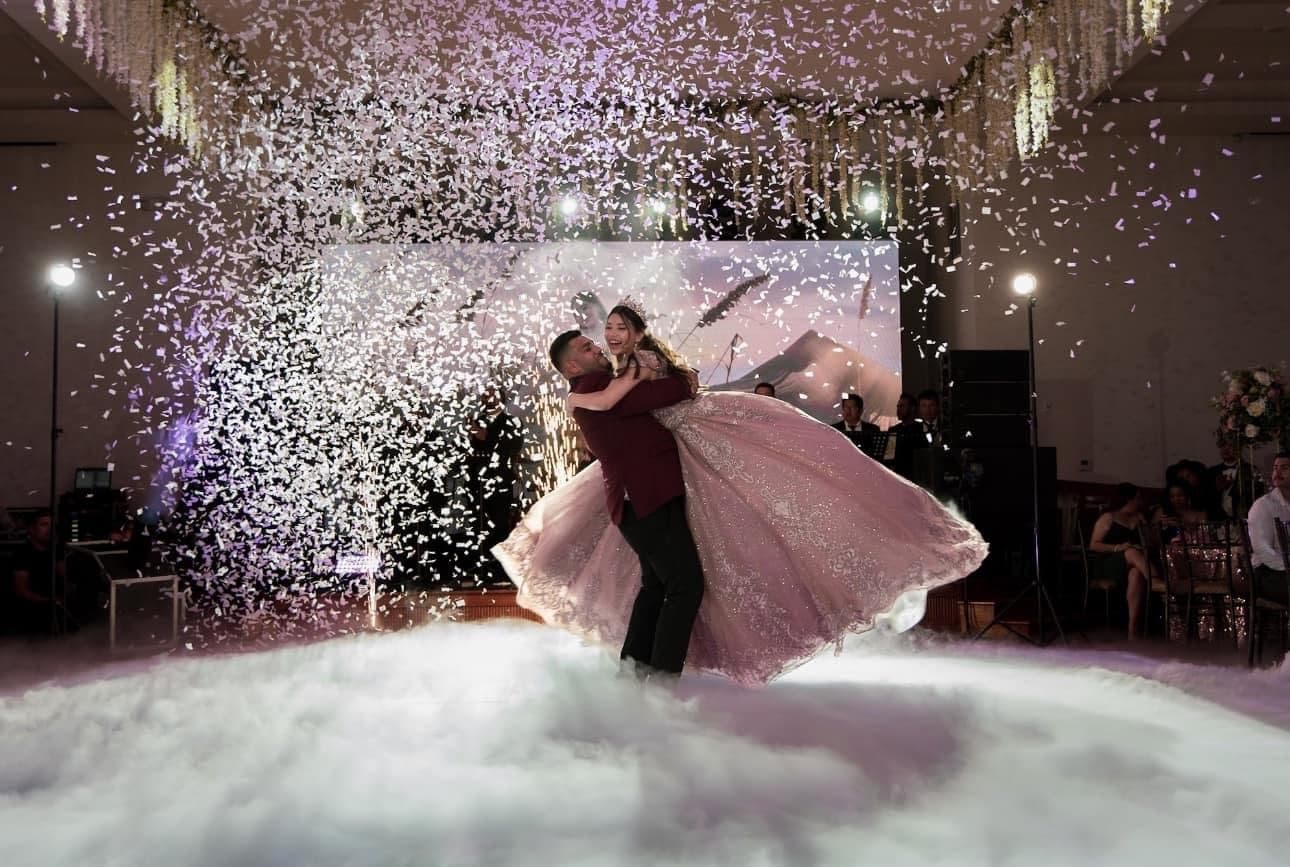Quinceañera lifted above a fog-covered dance floor beneath falling confetti