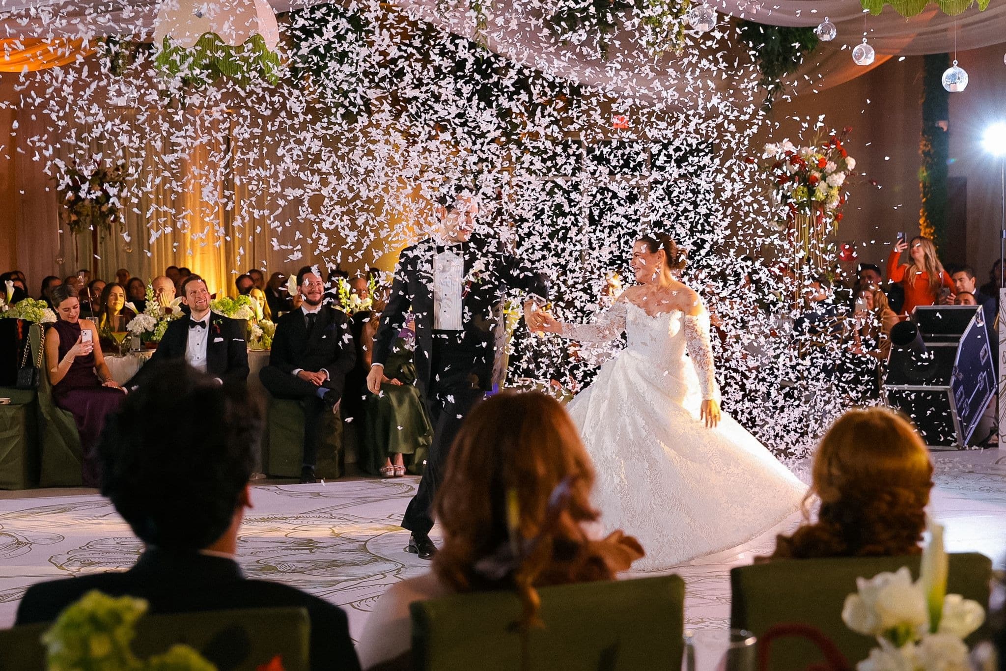 Bride and groom surrounded by falling confetti during a reception